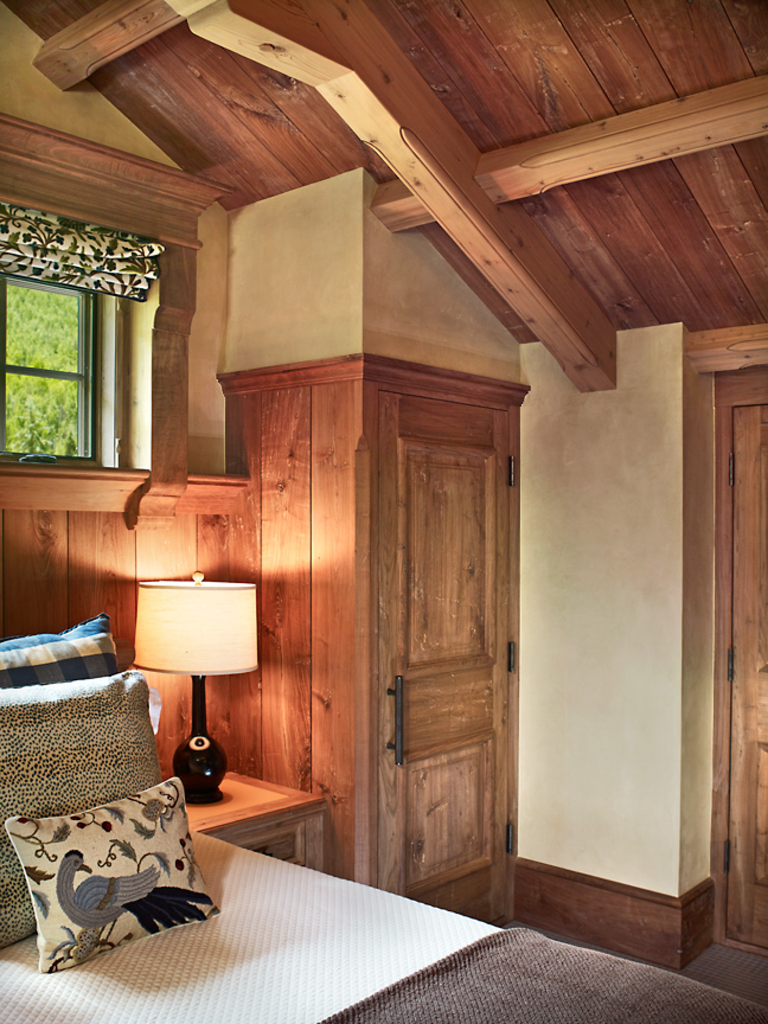 a corner of a rustic bedroom with wood beam ceilings and paneling at hornsilver