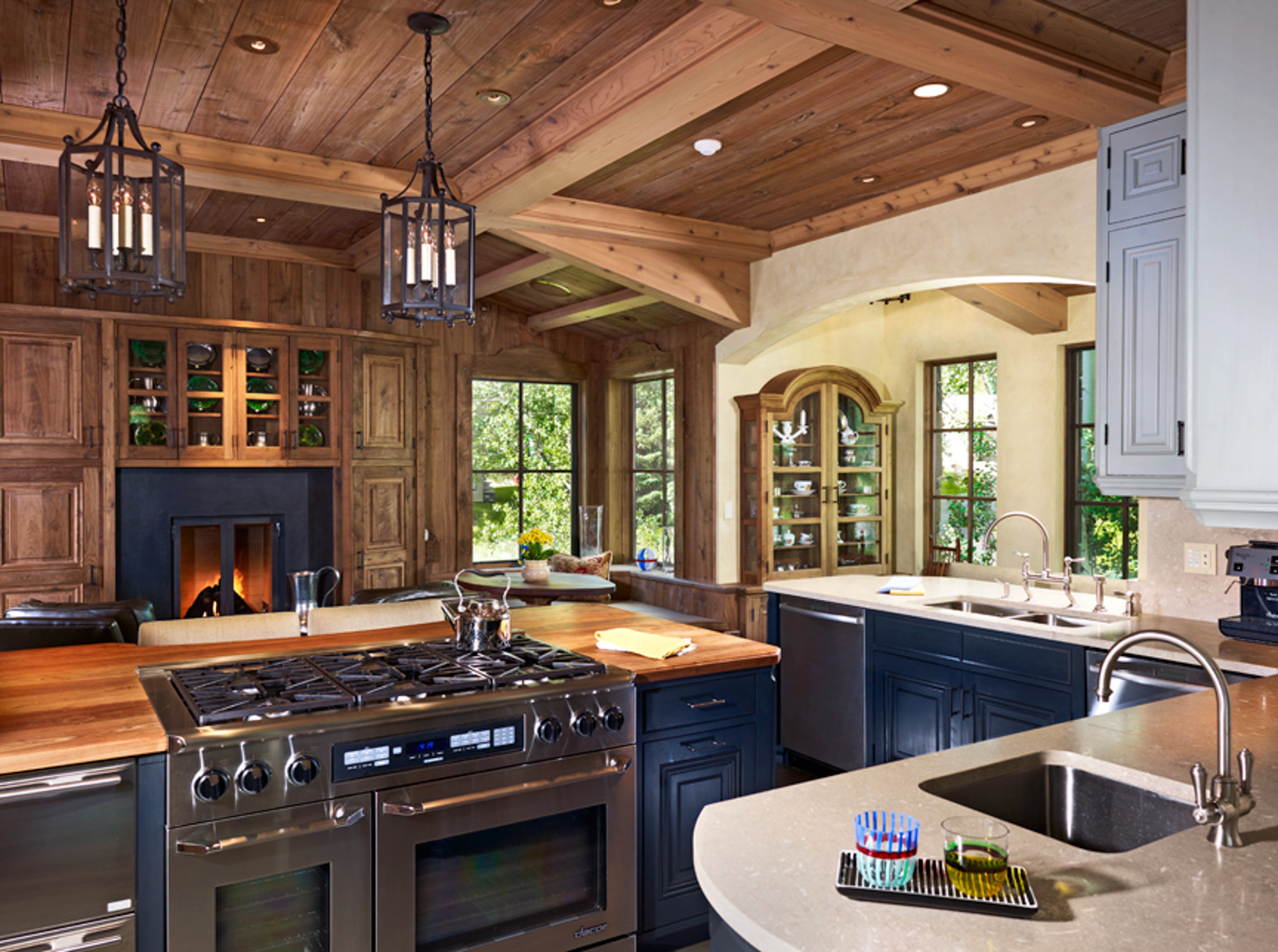 a rustic style kitchen with a fireplace and blue lower cabinets at hornsilver