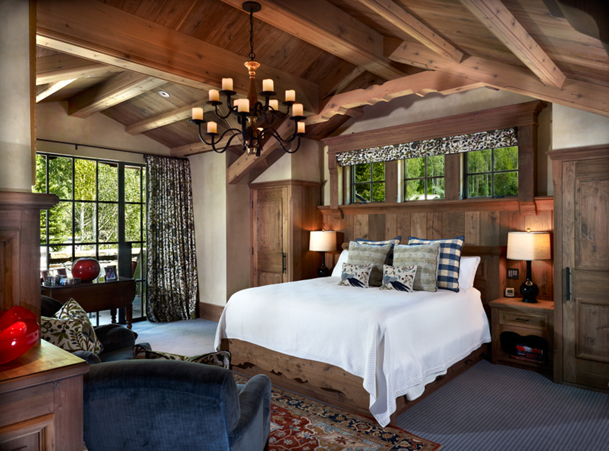 A large bedroom with elaborate wood beams in the ceiling and a wrought iron chandelier at hornsilver