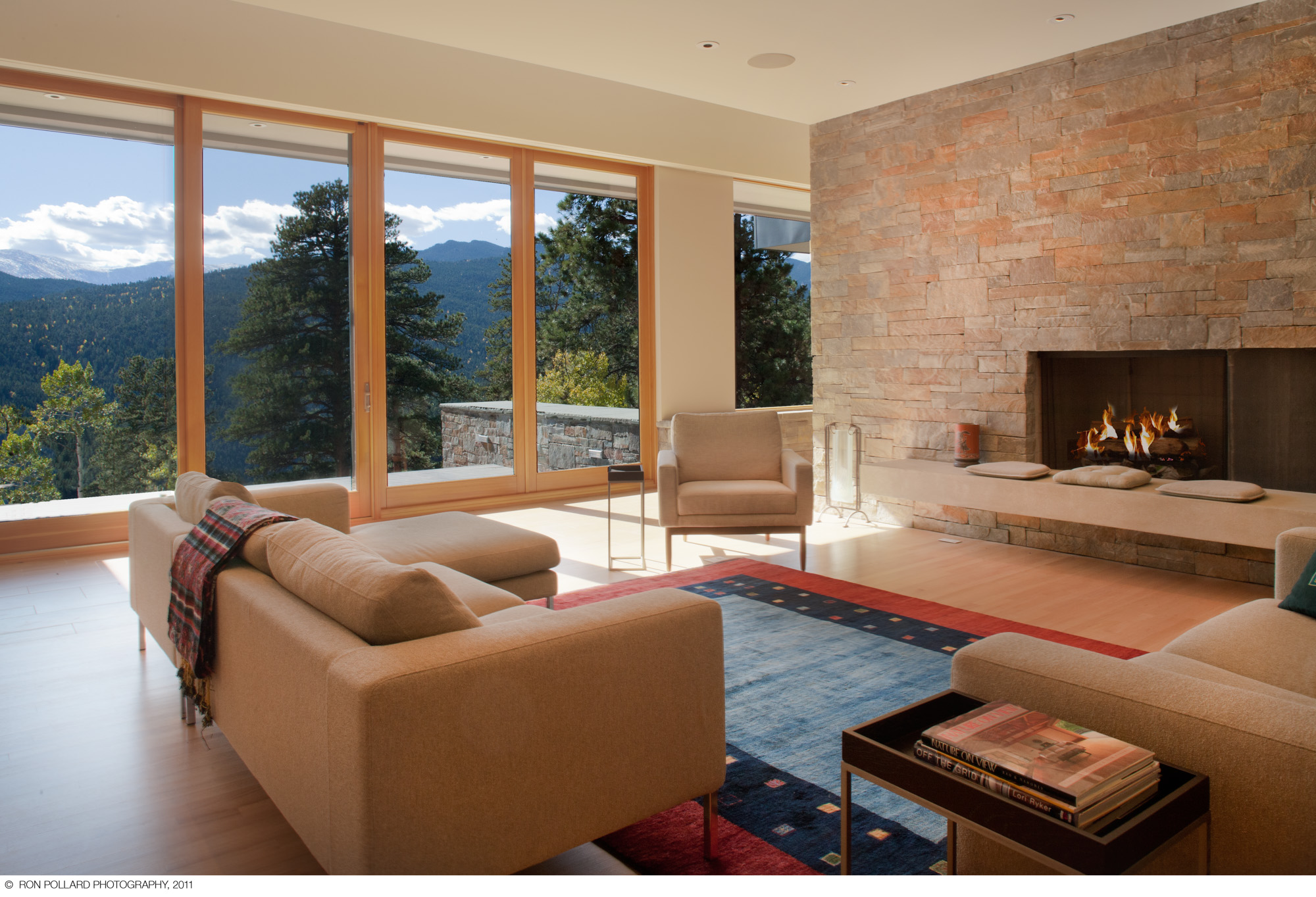 a living room with a large contemporary stone fireplace and floor to ceiling windows at williams ridge