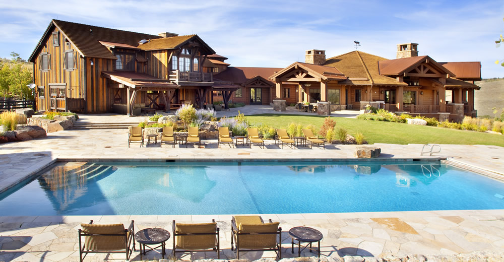 A large square pool in front of a large rustic colorado traditional home at royal elk