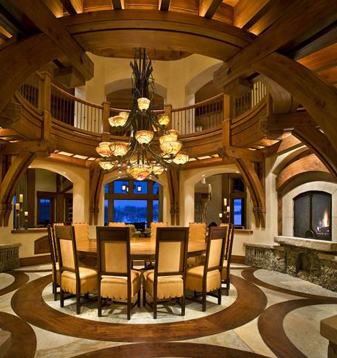 A circular dining table under a large stained glass chandelier with circular wooden flooring at royal elk