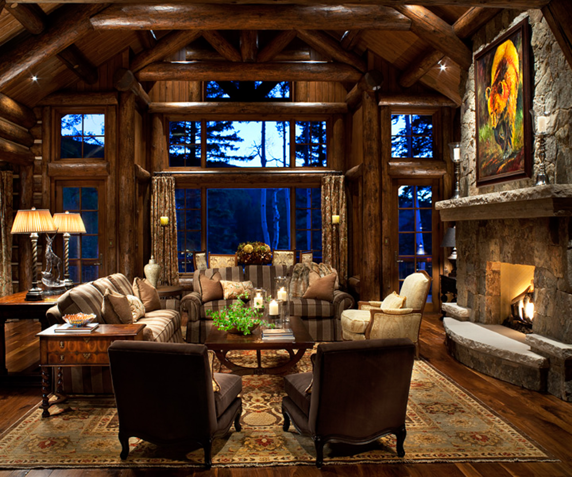 A view of a living room with stone fireplace and large windows at bachelor gulch