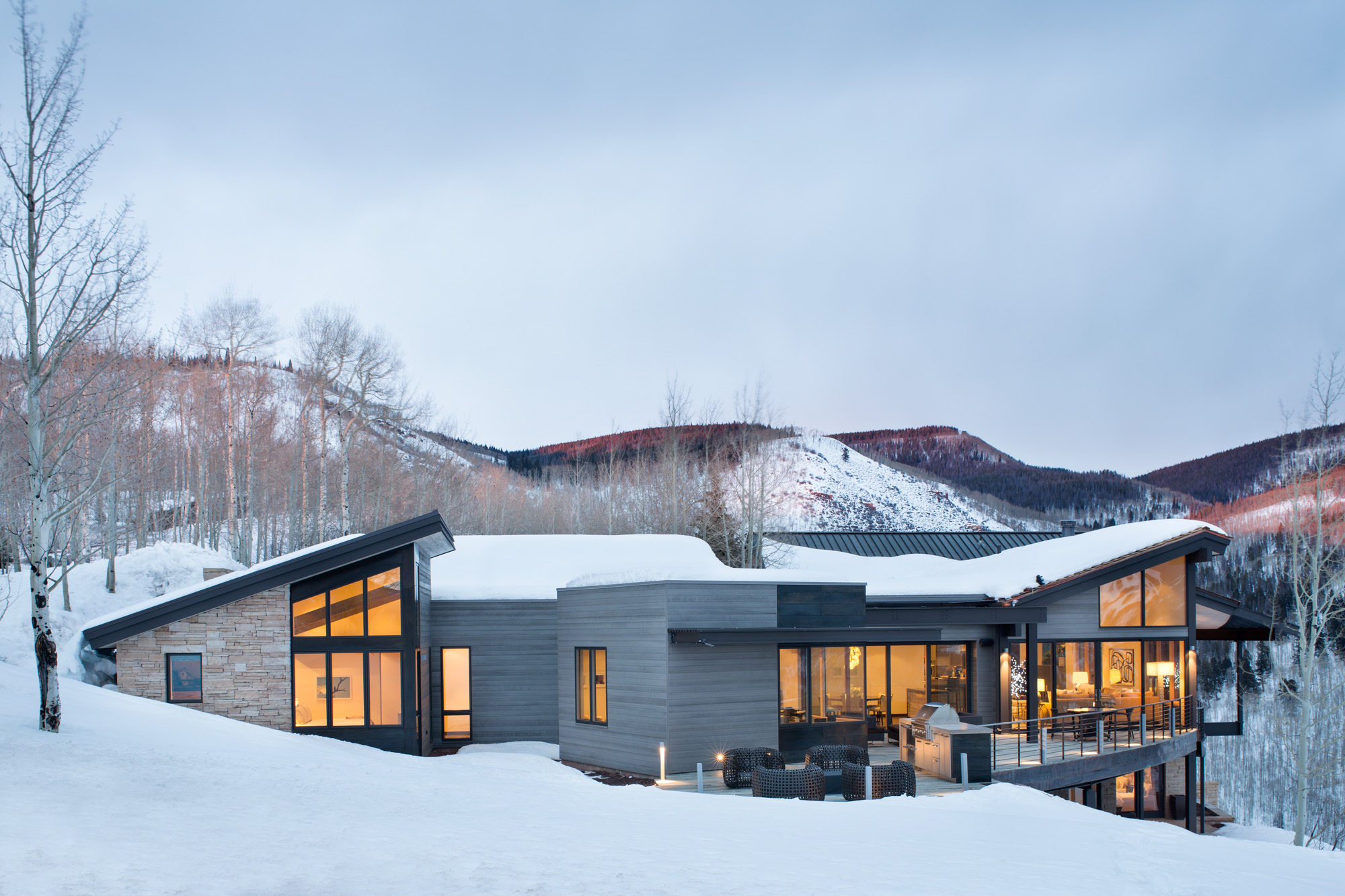 mountain star modern exterior photo of a grey modern home in the snow at dusk an example of mountain modern style